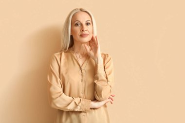 Mature blonde woman on beige background