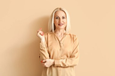 Mature blonde woman on beige background