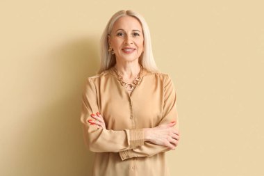 Mature blonde woman on beige background