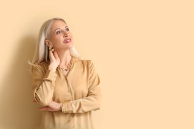 Mature blonde woman on beige background