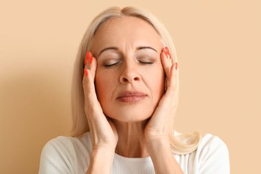 Mature blonde woman on beige background, closeup