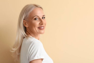 Mature blonde woman on beige background, closeup