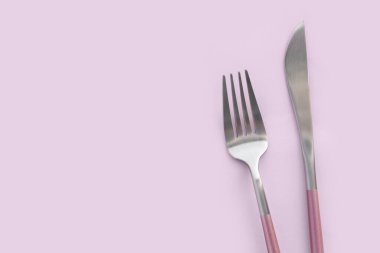 Pembe arka planda paslanmaz çelik çatal ve bıçak