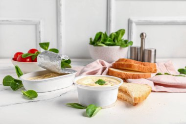 Duvar kenarındaki beyaz grunge masasında işlenmiş peynir, tost ve sebze kutuları.