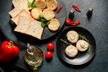 Koyu arkaplanda krem peynirli bir tabak lezzetli kızarmış ekmek.