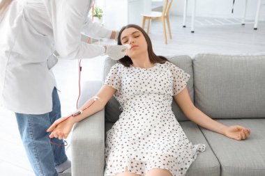 Baygın genç bir kadın kliniğe kan bağışlıyor.