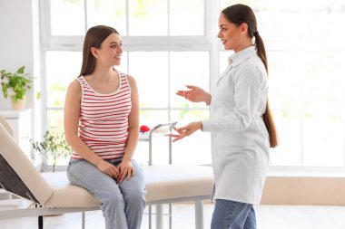 Kadın doktor klinikte genç kan bağışçısıyla konuşuyor.