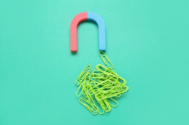 Yeşil zemin üzerinde ataç yığını olan mıknatıs