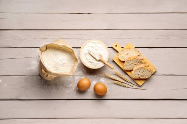 Gri ahşap zemin üzerinde ekmek, yumurta ve buğday unu dilimleri olan ahşap tahta tahta.