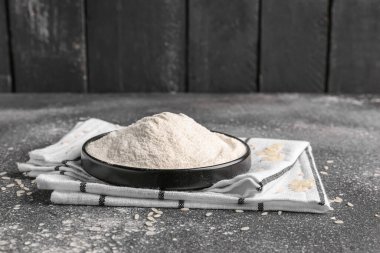 Tabakta pirinç ve un, duvarın yanındaki grunge siyah masada.