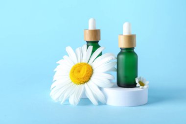 Renkli arka planda gerekli yağ şişeleri ve papatya çiçekleri kompozisyonu
