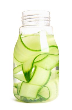 Beyaz arka planda dilimlenmiş salatalıkla doldurulmuş bir şişe su.