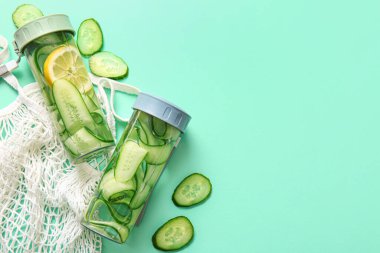 Turkuaz arka planda salatalık dilimli spor şişeleri.