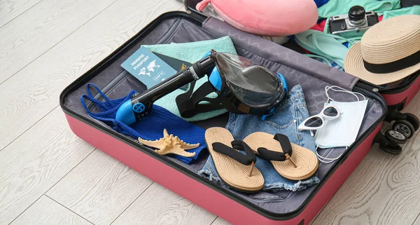 打开装有女性海滩配件 豁免护照和潜水面具的手提箱放在地板上 — 图库照片
