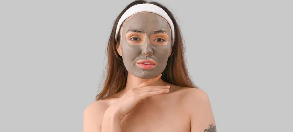 灰色の背景に適用粘土マスクを持つ若い女性 — ストック写真