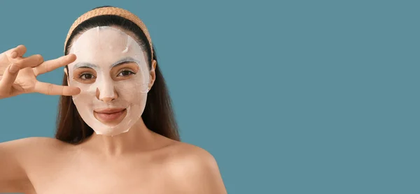 Ung Kvinna Med Tillämpad Sheet Ansiktsmask Visar Seger Gest Blå — Stockfoto
