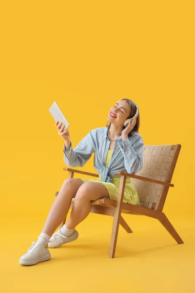 Young Woman Headphones Using Tablet Computer Wooden Armchair Yellow Background — Foto Stock