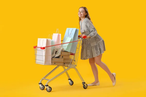 Vrouwelijke Verkoper Met Boodschappentassen Winkelwagen Gele Achtergrond — Stockfoto