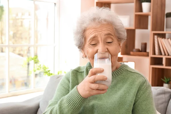 Senior woman drinking milk at home, closeup