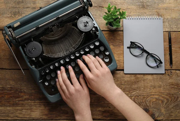 Vrouw Typend Schrijfmachine Met Bril Notitieboekje Kamerplant Bruine Houten Ondergrond — Stockfoto