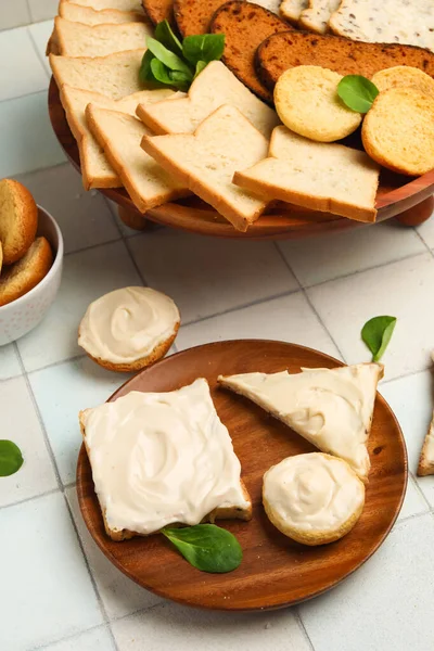 stock image Plate of tasty toasts and croutons with cream cheese on white tile background