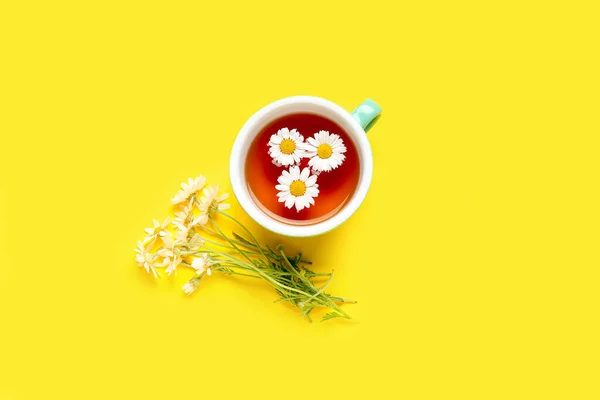 黄色の背景に天然カモミールティーと花のカップ — ストック写真
