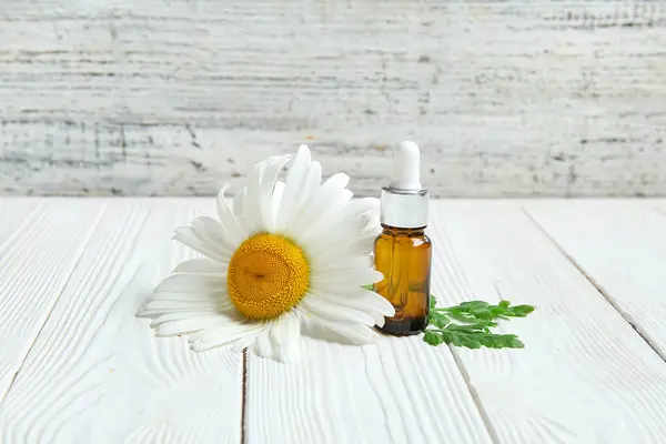 Flasche Ätherisches Und Kamillenblüte Auf Hellem Holztisch — Stockfoto