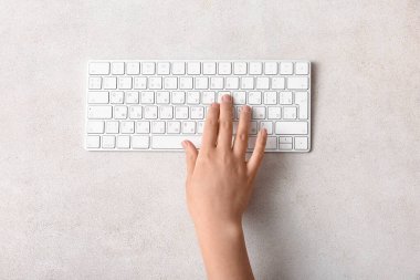 Işık arkaplanda modern bilgisayar klavyesine sahip kadın eli