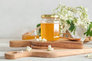 Hafif arka planda akasya çiçekleri olan bal kavanozu, yakın plan