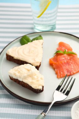 Krem peynirli lezzetli sandviçler ve mavi arka planda balıklar.