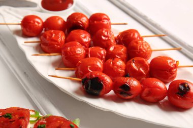 Beyaz arka planda lezzetli ızgara domatesli şiş tabağı.