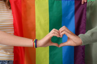 LGBT bayrağı taşıyan genç çift kalp yapıyor, yakın plan.