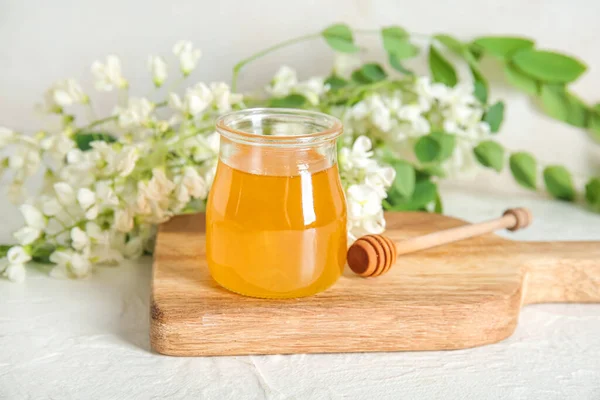 stock image Jar of honey with flowers of acacia and dipper on light background, closeup