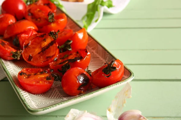 stock image Plate with tasty grilled tomatoes and arugula on green wooden background