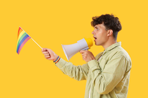 Young man with LGBT flag shouting into megaphone on yellow background