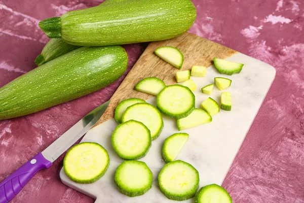 Frische Grüne Zucchini Und Brett Mit Scheiben Auf Violettem Hintergrund — Stockfoto