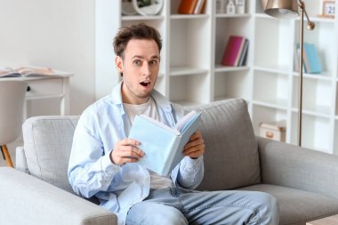 Evdeki kanepede kitap okuyan genç adam şok oldu.