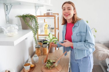 Genç bir kadın mutfakta sebze salatası yapıyor.