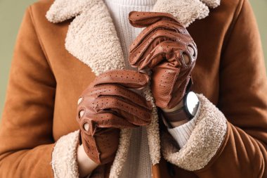 Yeşil arka planda deri eldivenli şık genç bayan, yakın plan.