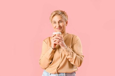 Pembe arka planda kahve fincanı olan olgun bir kadın.