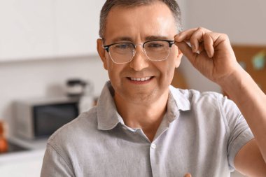 Mutfakta gözlüklü olgun bir adam, yakın plan.