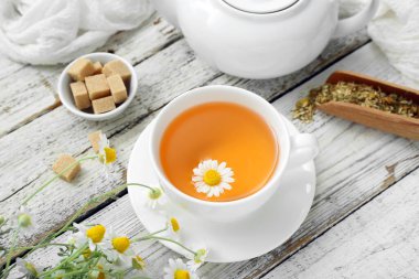 Hafif ahşap arka planda bir fincan sıcak papatya çayı.