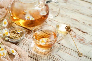 Hafif ahşap arka planda bir fincan sıcak papatya çayı.