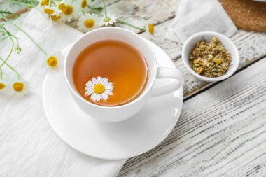 Hafif ahşap arka planda bir fincan sıcak papatya çayı.