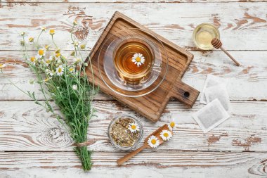 Hafif ahşap arka planda bir fincan sıcak papatya çayı.