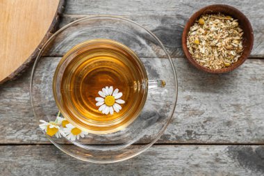 Tahta arka planda bir fincan sıcak papatya çayı.