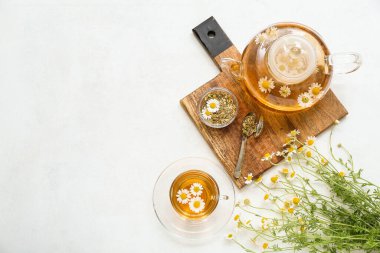 Hafif arkaplanda bir fincan sıcak papatya çayı ve çaydanlık.