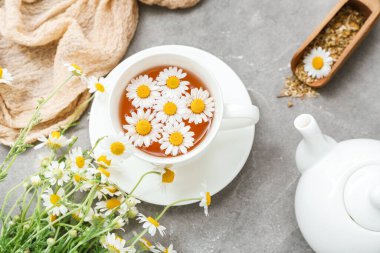 Gri arkaplanda bir fincan sıcak papatya çayı