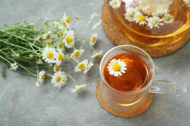 Gri arkaplanda bir fincan sıcak papatya çayı