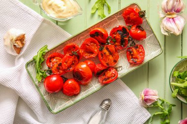 Lezzetli ızgara domates ve yeşil ahşap kaplama roka tabağı.